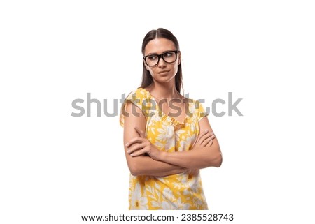 a young woman dressed in a yellow sundress and with glasses for vision looks to the side