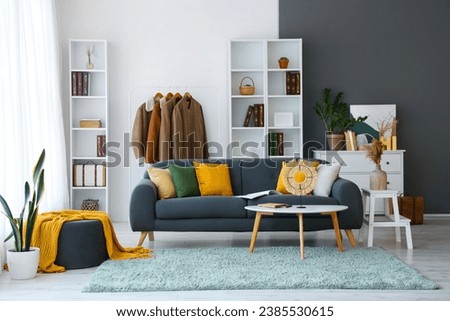 Interior of living room with black sofa and clothes rack Royalty-Free Stock Photo #2385530615