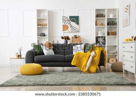 Interior of modern living room with grey sofa, warm blanket and umbrellas Royalty-Free Stock Photo #2385530671