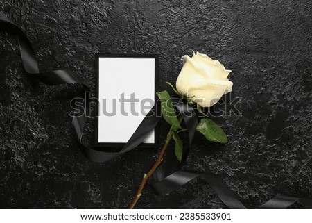 Beautiful white rose with black ribbon and photo frame on black grunge background