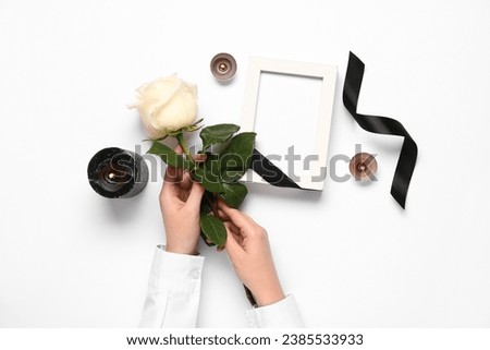 Female hands with rose, candles and photo frame on white background