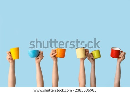 Women holding cups of hot coffee on blue background Royalty-Free Stock Photo #2385536985