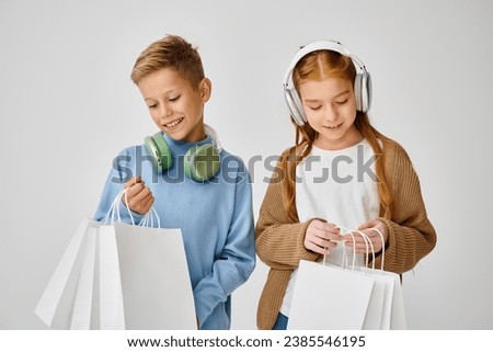 jolly little friends with headphones looking in their present bags, Black Friday, fashion concept Royalty-Free Stock Photo #2385546195