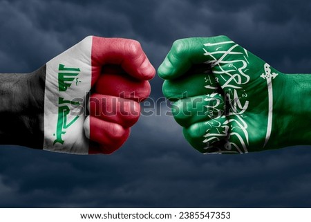 IRAQ vs SAUDI ARABIA confrontation, religious conflict. Men's fists with painted flags of IRAQ and SAUDI ARABIA. Dark clouds background