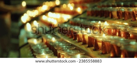 Many burning candles with blurred glowing background in the darkness.
