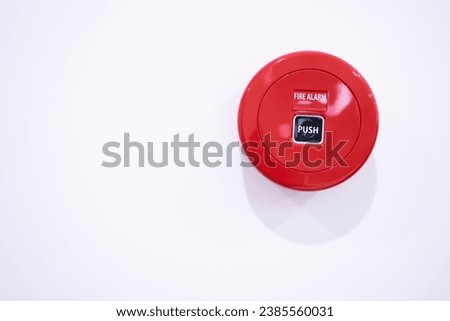 Red fire alarm push button on white wall background. Royalty-Free Stock Photo #2385560031