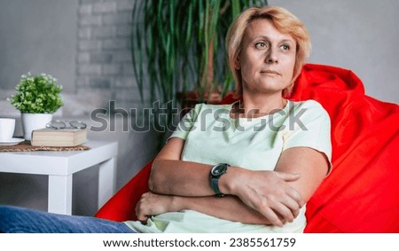 Close up photo of happy mature middle aged woman sitting on a chair at home in living room relaxing. Success and satisfaction lifestyle female retirement have rest leisure activity