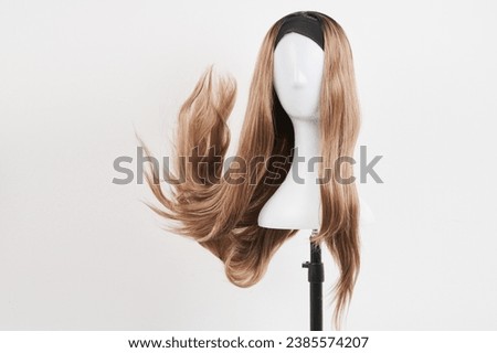 Natural looking dark blonde wig on white mannequin head. Long fair hair cut on the plastic wig holder isolated on white background Royalty-Free Stock Photo #2385574207