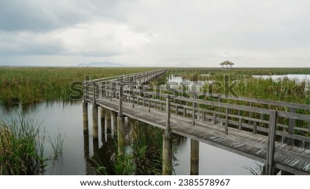 Wooden walkway and pavilion in the middle of freshwater marsh, blue sky, cloudy and prohibition Signs. Sam Roi Yot Freshwater Marsh or Bueng Bua Khao Sam Roi Yot National Park in Thailand. Royalty-Free Stock Photo #2385578967