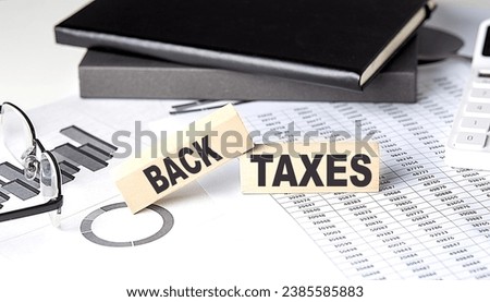 BACK TAXES - text on wooden block with chart and notebook