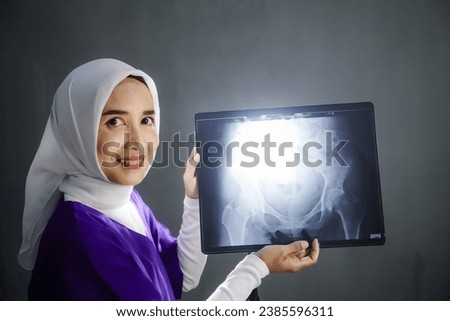 Asian hijab nurse wearing purple medical uniform showing the result of  x-ray. Weist x-ray, radiology person,  health-care and medical.
