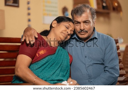 Indian senior husband consoling his worried crying wife at home - concept of emotional family support, companionship and kindness