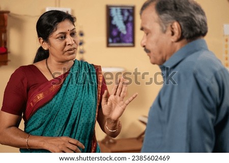Shoulder shot of worried furious middle aged wife arguing with husband at home - concept of family or relationship problems, communication and distrust. Royalty-Free Stock Photo #2385602469
