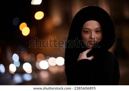 Muslim woman walking on an urban city street on a cold winter night wearing hijab