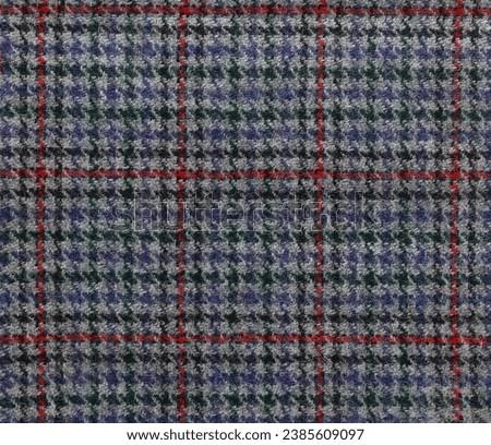 A houndstooth tartan pattern on woolen cloth in grey red and blue