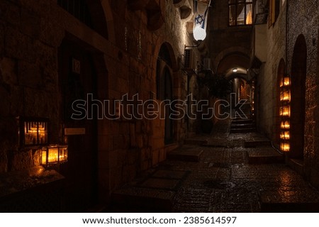 Burning Hanukkah candles cast a glow on the cobblestone streets of the Old City of Jerusalem on the eighth night of the Festival of Lights in Israel.  Royalty-Free Stock Photo #2385614597