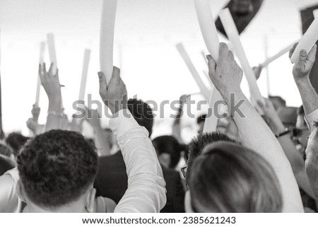 People celebrating New Year's Eve, wedding, birthday or any event. Black and white picture of people rising arms holding a light tube. 