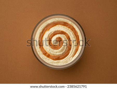 Cream cheese with caramel cream swirl on brown background, top view