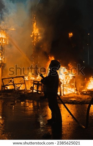 Firefighter in action, fighting very strong fire, against light, dangerous, extinguishing fire
