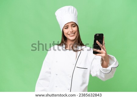 Young chef caucasian woman over isolated background making a selfie
