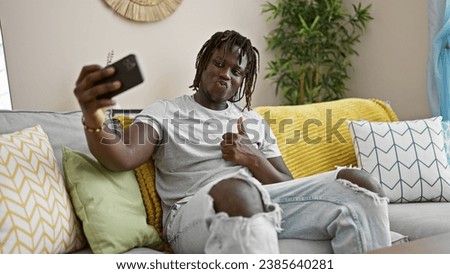 African american man taking selfie picture with smartphone doing thumb up gesture at home