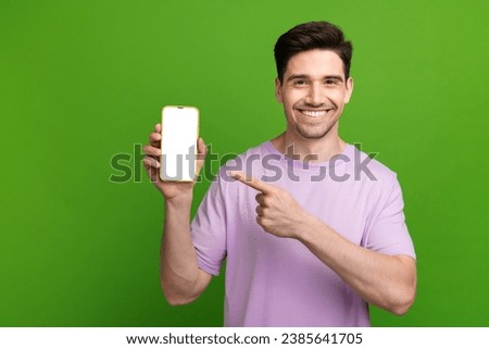 Photo portrait of attractive young guy hold device point white screen dressed stylish purple clothes isolated on green color background