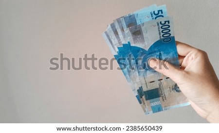 Woman's hand is making a payment. Indonesian rupiah currency (Rp. 50.000 Lima puluh ribu rupiah), Fifty thousand Indonesian rupiah money isolated on white background.