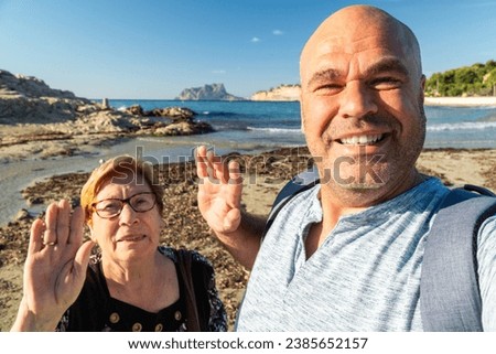 Man with his grandmother takes a selfie enjoying the beach