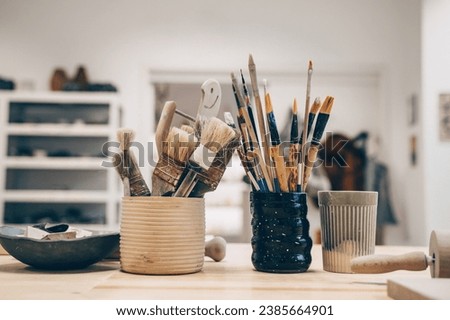 Equipment for creating handmade dinnerware on workbench at art studio. Ceramic pottery objects and hand tools in handcraft workshop. Minimalist ceramic tablewares and supplies in ceramic class.