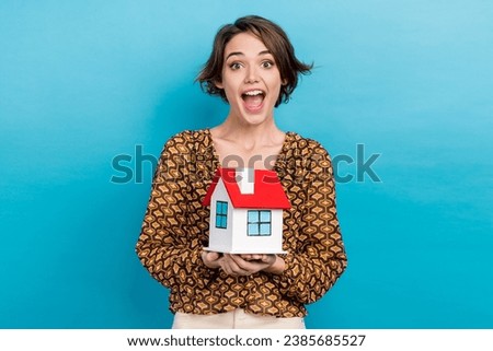 Photo of young funny reaction girl holding her first ownership building apartment open mouth speechless isolated on blue color background