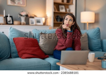 Young woman entrepreneur with coffee cup and laptop on desk thinking ideas while sitting at home.