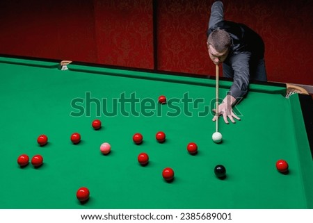 A skilled snooker player engaged in a captivating game of precision and strategy. Royalty-Free Stock Photo #2385689001
