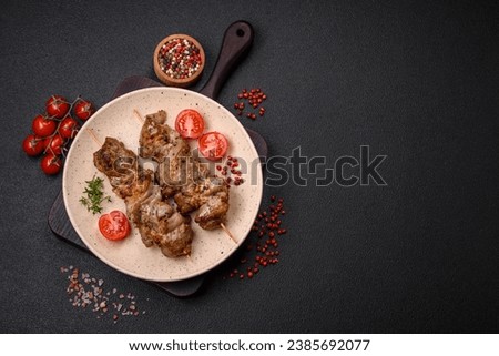 Delicious fried shish kebab of chicken or pork meat with salt, spices and herbs on a dark concrete background