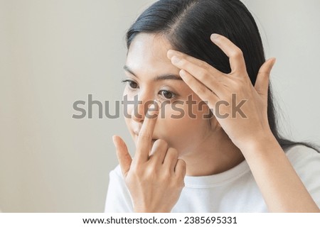 Ophthalmology care, eye sight or vision. Closeup asian young woman, female hand holding and putting, wearing soft contact lens on face with finger, look into eye on background. Medicine and health. Royalty-Free Stock Photo #2385695331