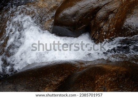 The waterfall flowing through the rocks in nature is a quiet stream with no people taking pictures.