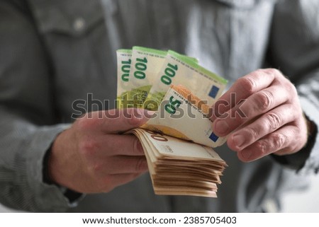 
a man holds euro money in his hand and counts them. close-up view on a blurred background