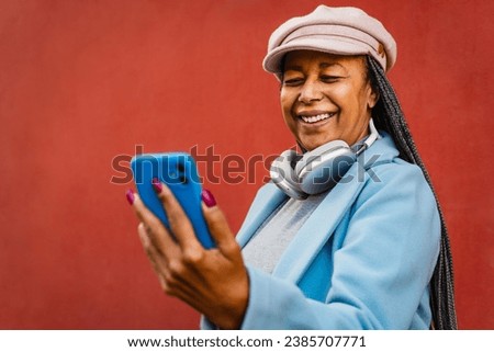 Senior African woman having fun using mobile smartphone outdoor Royalty-Free Stock Photo #2385707771