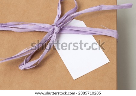 Mockup of a tag on a brown craft box with a ribbon. Space for text, copy space. Empty postcard layout
