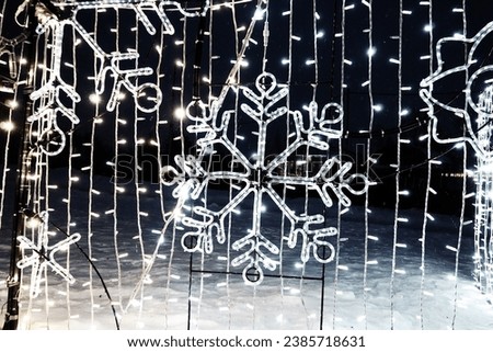 New Year Christmas illumination of city streets. Flashing, flickering, shining, gleaming of electric bulbs and lights. Beautiful garlands and architectural forms. LED energy-saving garlands snowflakes