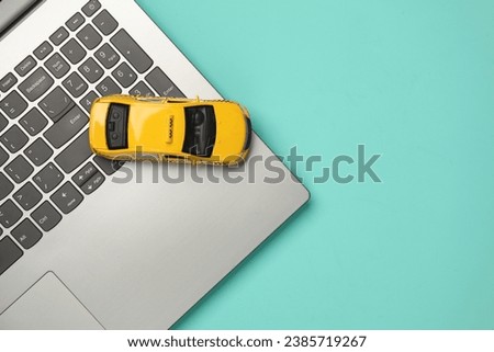Toy taxi car model with laptop on blue background. Top view
