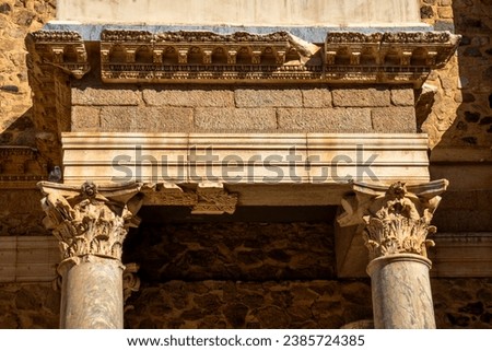 Ornate cornice with perched dove of the Roman Theater of Mérida with Greek and Roman marble columns, and a needle trap on the cornice so that pigeons do not spoil the monument. Royalty-Free Stock Photo #2385724385