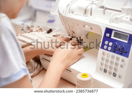 A woman seamstress sews things from fabric on a CNC sewing machine.