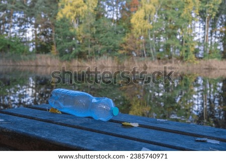 forgotten garbage plastic bottle in the park on a bench near the lake