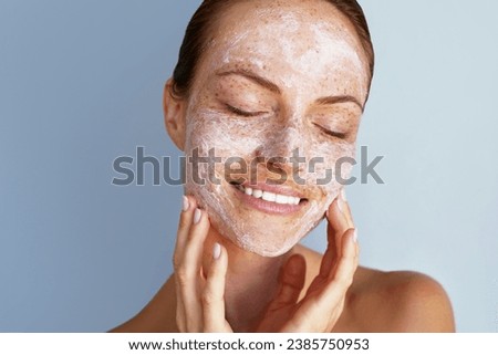 Self love. Skin care beauty portrait. Facial scrub, young happy woman with a freckles is applying white peeling cosmetic product to whole her face. Daily skincare routine. Dermatology. Exfoliating Royalty-Free Stock Photo #2385750953