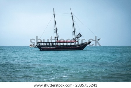 Pirate ship on the high seas, horizontal landscape photo, Tour boat, Piracy on the beach. Brazilian Sea, Ilha Bela. Calm sea. Royalty-Free Stock Photo #2385755241