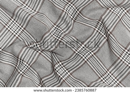 Crumpled, wrinkled fabric of black and brown colors in tartan check close-up. Traditional Scottish clothing. place for your design Royalty-Free Stock Photo #2385760887