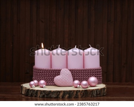 First Advent: Advent decoration on a wooden disc decorated with pink candles and Christmas balls.