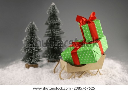 Santa Claus's sleigh in the snow. There are gifts in the sleigh. two Christmas trees next to each other