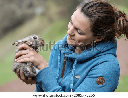 Attractive woman with a rabbit. Happy woman holding a cute rabbit. Easter bunny. Spring photo of beautiful young woman with her rabbit. Woman holding cute rabbit.