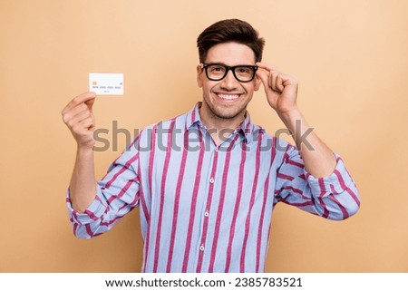 Photo of cheerful banker holding plastic card demonstrating new features cashless transaction payment isolated on beige color background